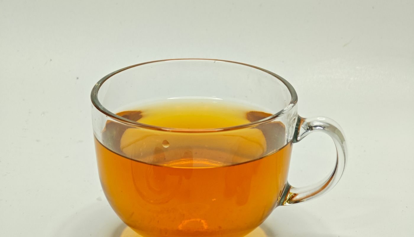 A glass cup of ginger and lemon tea with honey